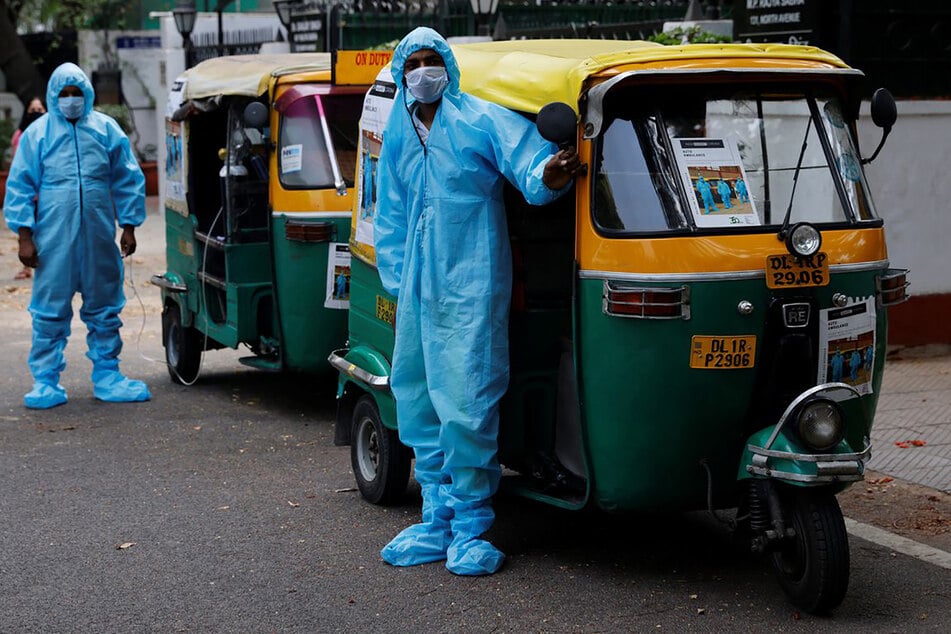 Indien, Neu Delhi: In Schutzanzügen und mit Mund-Nasenschutz stehen Fahrer vor Rikscha-Krankenwagen, mit denen sie Corona-Patienten gratis durch die Hauptstadt Neu Delhi bringen.