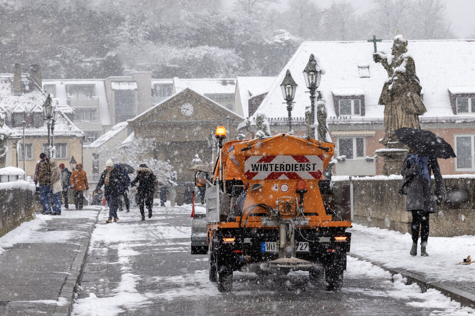 Ein Räumfahrzeug befreit die alten Mainbrücke in Würzburg von Schnee und Eis.