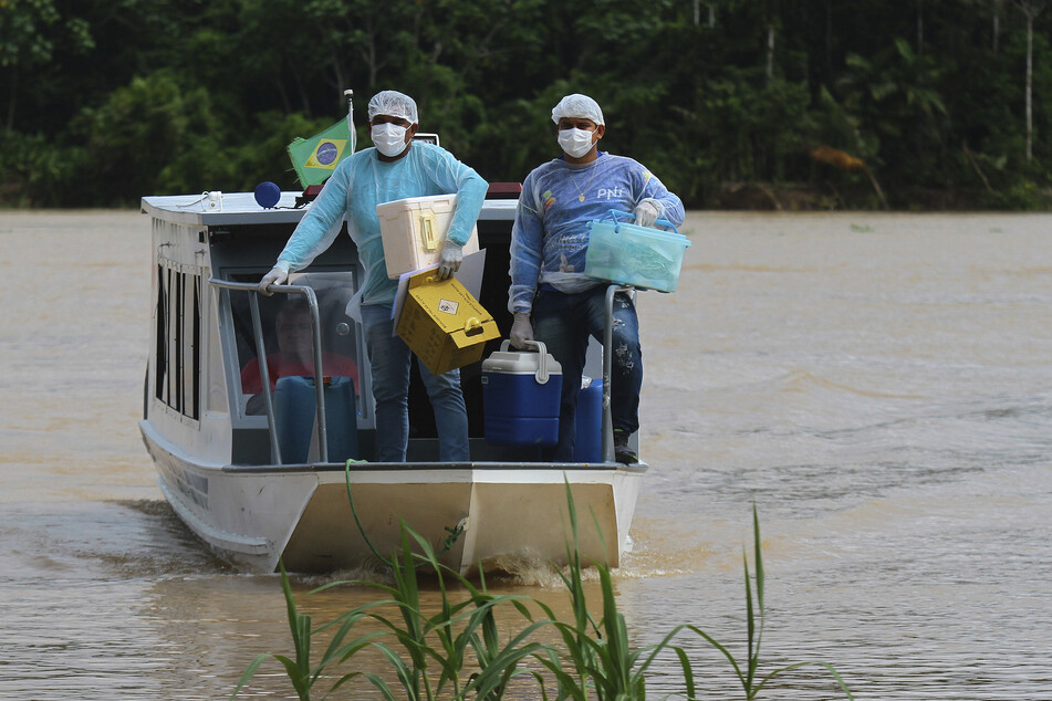 Brasilien, Labrea: Die medizinischen Mitarbeiter Diego Feitosa Ferreira (r) und Clemilton Lopes de Oliveira kommen auf einem Boot in der Gemeinde Santa Rosa im brasilianischen Bundesstaat Amazonas an, um dort die Bewohner mit dem Corona-Impfstoff von AstraZeneca zu impfen.