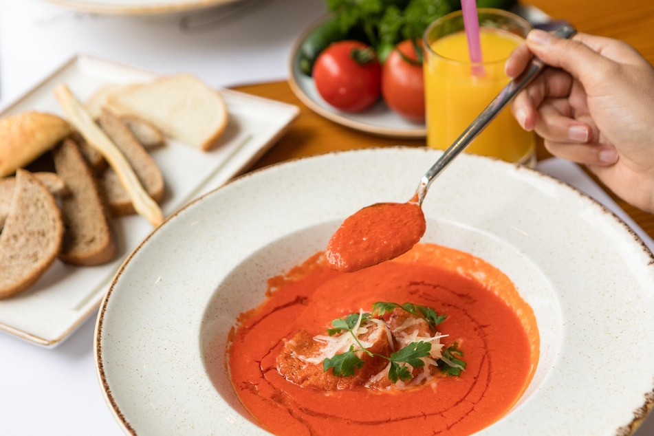 Tomato soup goes well with bread and basil leaves.