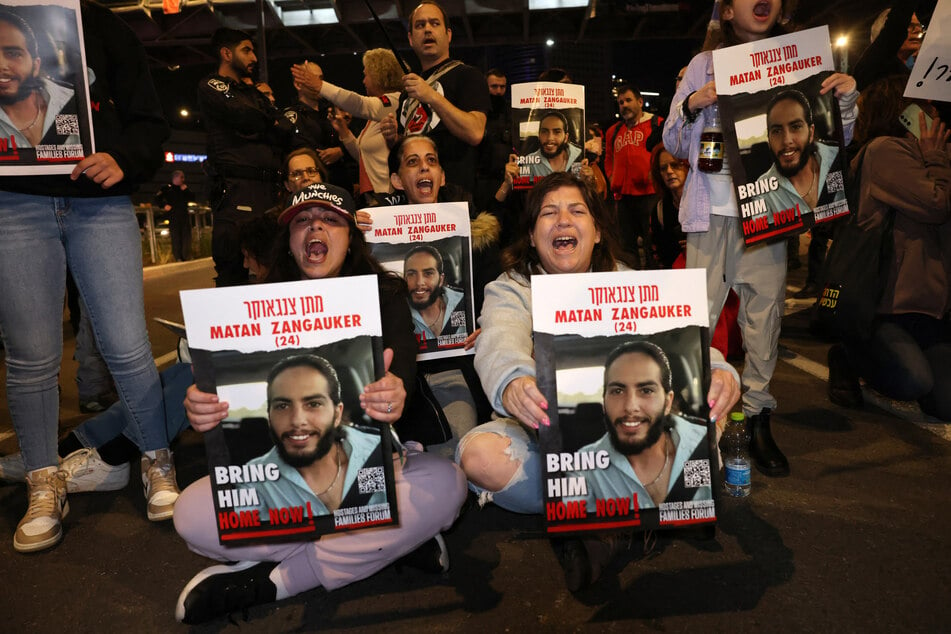 Freed Israeli former hostage Ilana Gritzewsky (seated L) joins relatives and supporters holding placards bearing portraits of Israeli hostage Matan Zangauker in Tel Aviv on January 20, 2023.