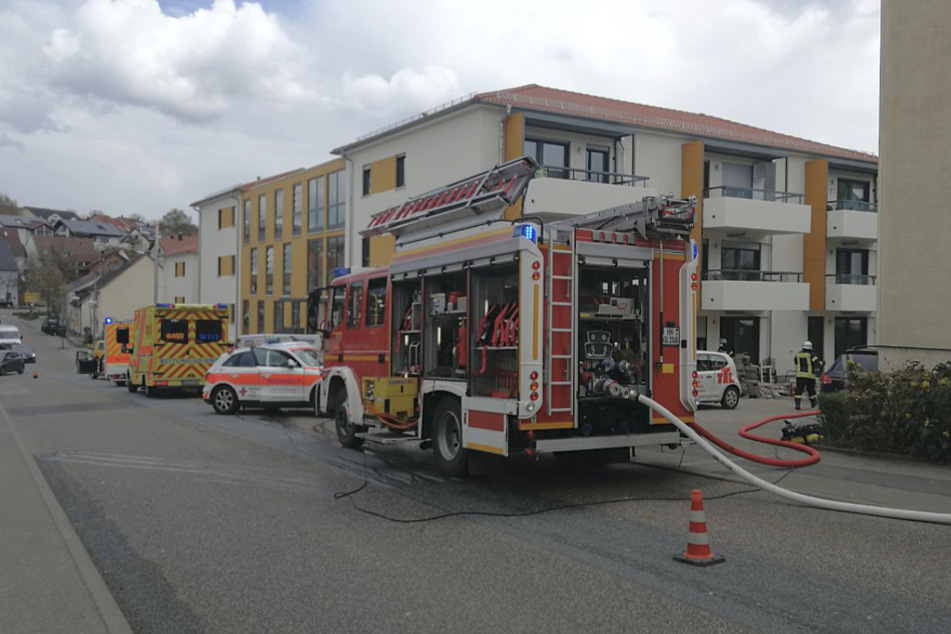 Feuerwehreinsatzkräfte stehen vor dem Haus, in dem es zu einem Brand in einer Wohnung kam.