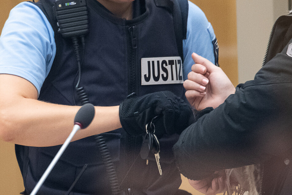 Eine Justizbeamtin schließt während des Beginns eines Prozesses gegen eine IS-Rückkehrerin die Handschellen auf. (Archivbild).