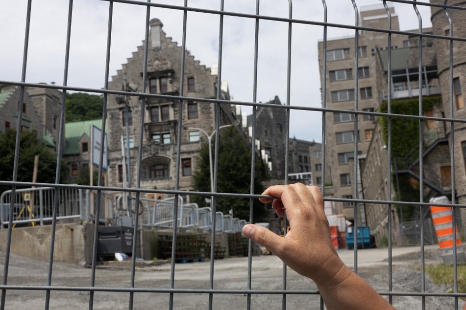 Kwetiio looks through a fence at the Royal Victoria Hospital construction site in Montreal, Canada.