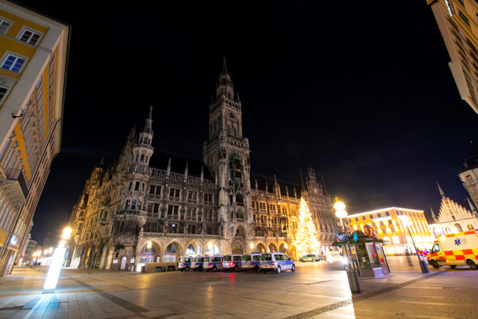Polizisten und Sicherheitsmitarbeiter der MVG stehen auf dem ansonsten menschenleeren Marienplatz im Zentrum der Stadt.