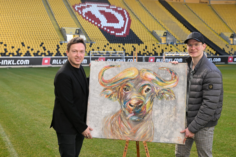 Stadionmanager Ronald Tscherning (43, l.) und Künstler Dominik Domke (21) präsentieren auf dem Dynamo-Rasen das Wasserbüffel-Bild "Oxymoron".