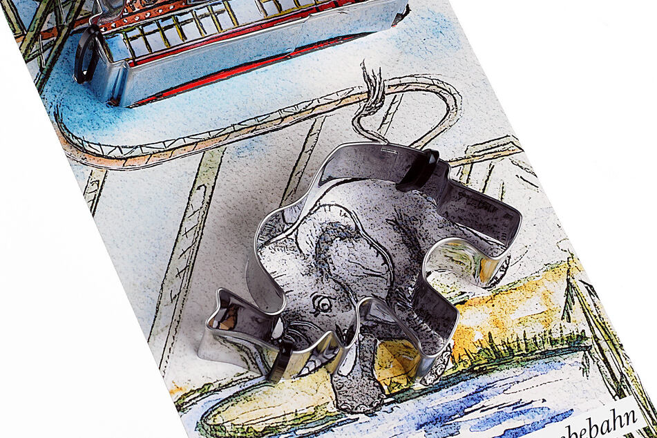 Ein Plätzchenausstecher der Schwebebahn und des Elefanten Tuffi liegen auf einem Tisch.
