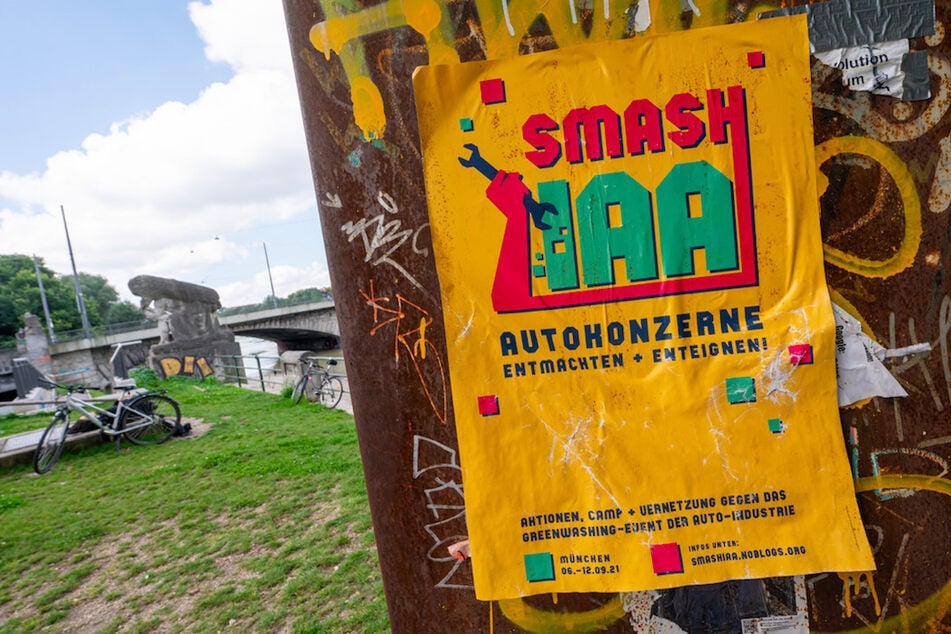 Ein gelbes Plakat mit der Aufschrift "Smash IAA Autokonzerne entmachten und enteignen!" klebt an einer Wand in der Stadt.