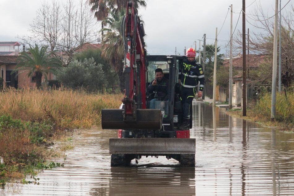 Mit einem Bulldozer bahnen sich Mitarbeiter des Zivilschutzes einen Weg durch das Wasser.