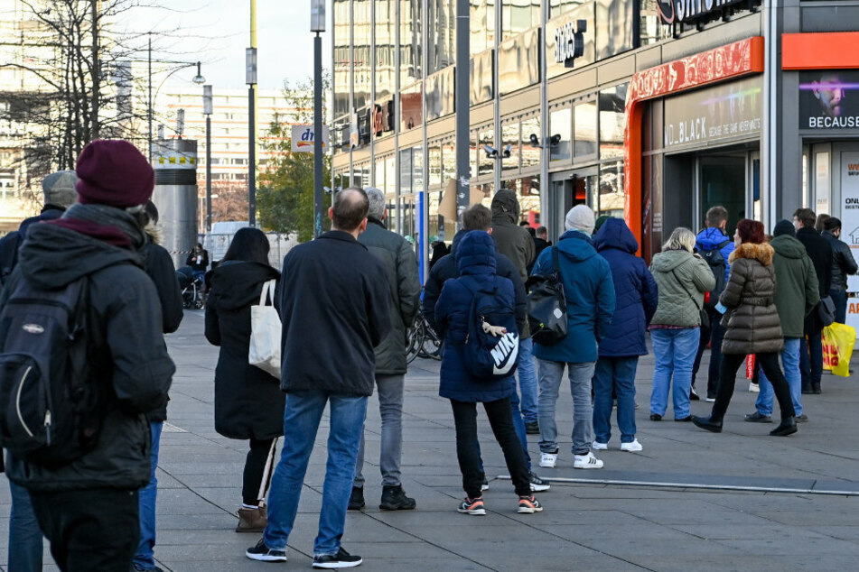 Zahlreiche Menschen stehen auf dem Alexanderplatz vor einem Elektronik-Fachmarkt.