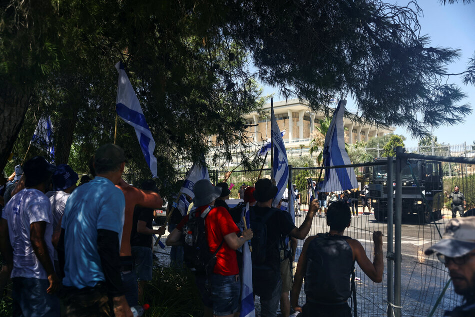 Protesters look through a police barrier during a demonstration against Israeli Prime Minister Benjamin Netanyahu and his nationalist coalition government's judicial overhaul.