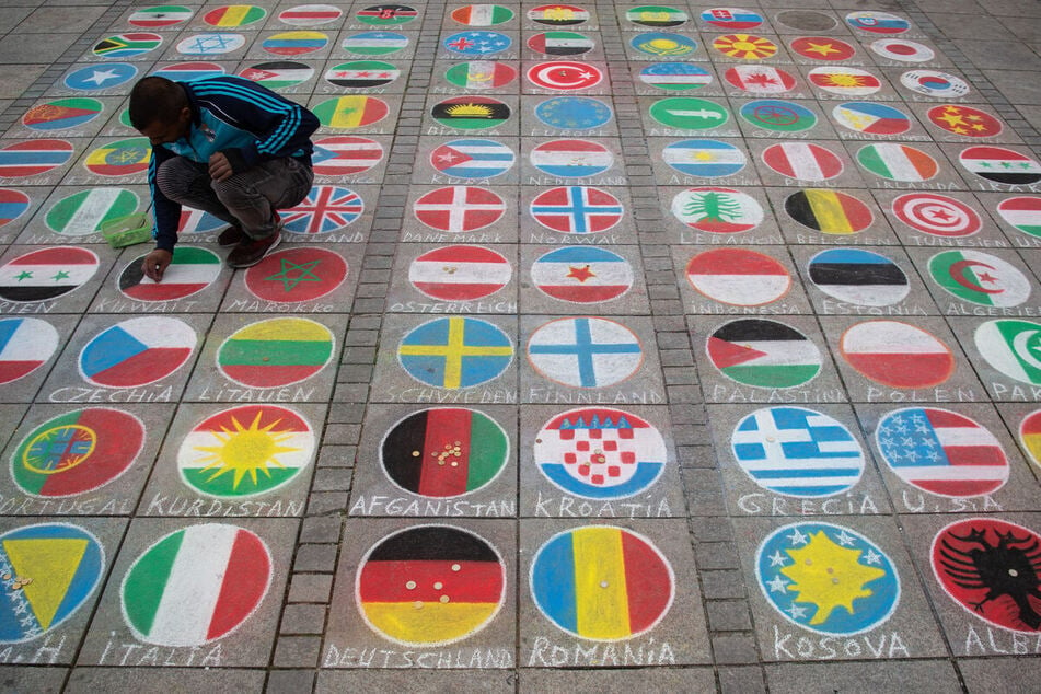 Kreidemalerei in Stuttgart: Ein Künstler malt internationale Flaggen auf die Straße.