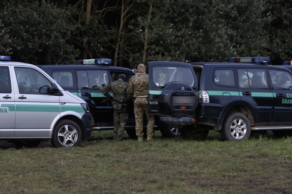 Polizeibeamte stehen an der polnischen Grenze, an der sich mehrere Dutzend Flüchtlinge befinden. Ein fünf Jahre altes Kind ist dort in einem Auffanglager durch einen giftigen Pilz ums Leben gekommen.