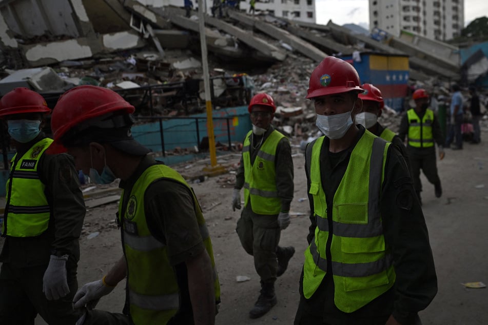 Rescuers of the Bolivarian National Armed Forces of Venezuela walk at the site of a collapsed building in Caraballeda, La Guaira State, on June 28, 2026, following twin earthquakes.