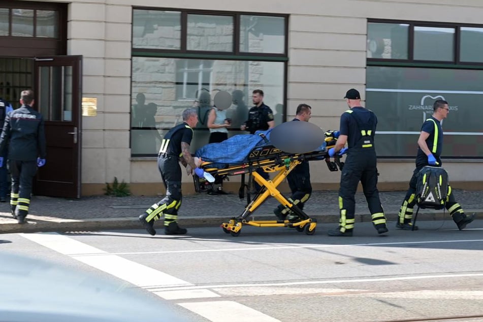 Noch mit dem Messer im Rücken wird der Zahnarzt zum Rettungswagen gebracht.