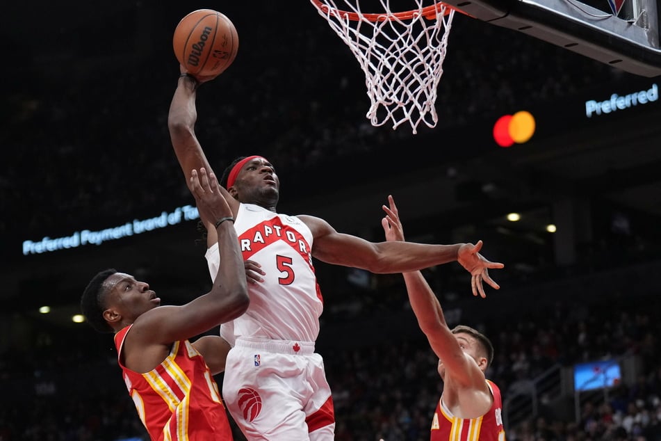 Toronto Raptors forward Precious Achiuwa dunks (c.) as Atlanta Hawks forward Onyeka Okongwu (l.) defends.