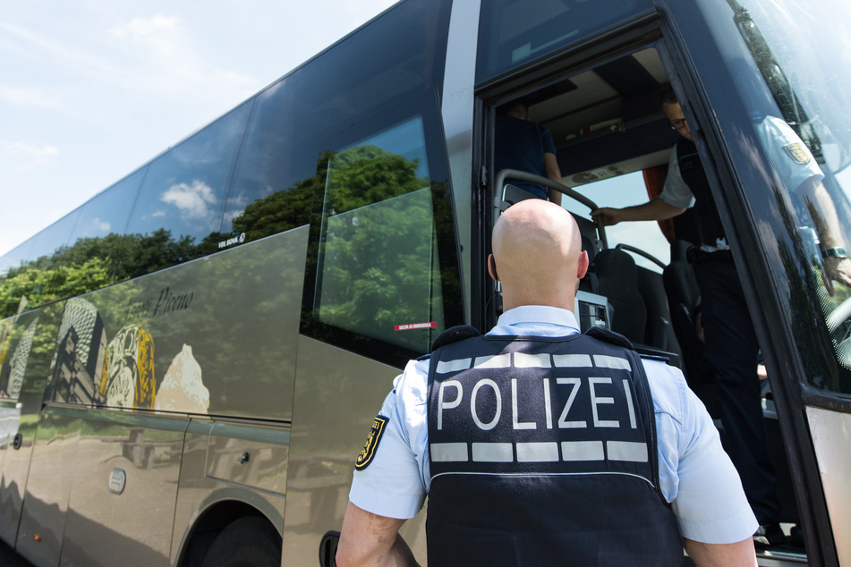 Ein Polizist steht während einer Verkehrskontrolle vor der geöffneten Tür eines Fernbusses. (Symbolfoto)