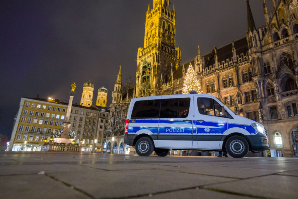 Ein Polizeiwagen fährt über den menschenleeren Marienplatz im Herzen Münchens.