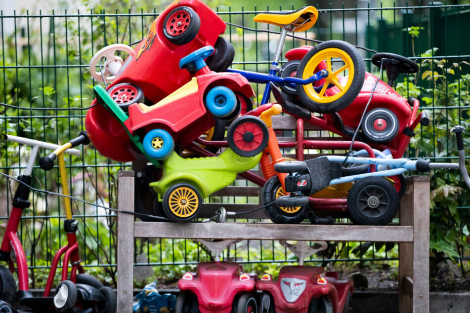 Bobby-Cars, andere Spielautos und Gefährte für Kinder liegen angeschlossen vor einer Kita in Berlin-Wilmersdorf auf einem Stapel.