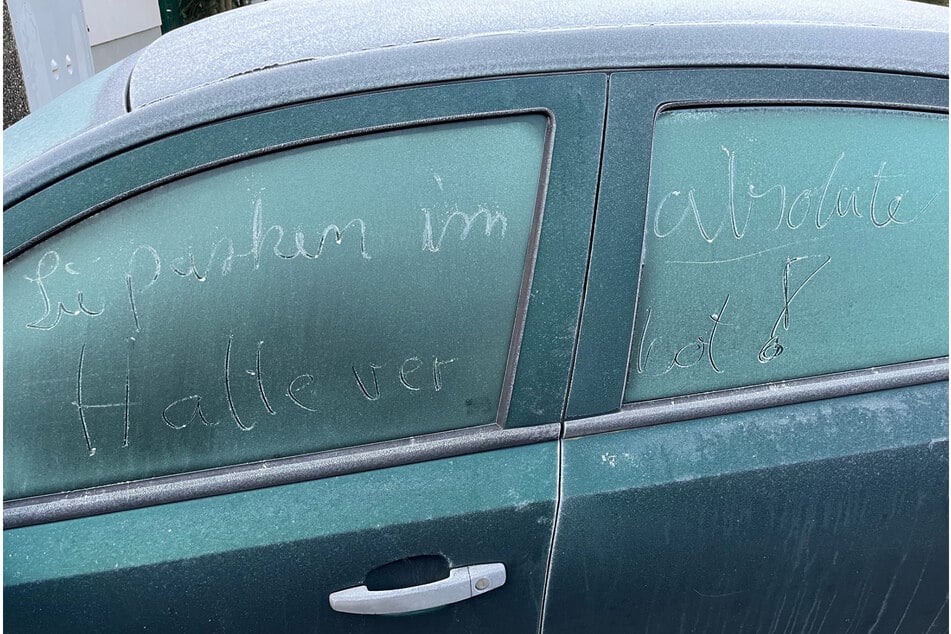 Auf der vereisten Scheibe steht geschrieben: "Sie parken im absoluten Halteverbot!"