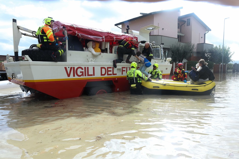 Helfer bringen Opfer der Überschwemmung durch ein Unwetter in einem Schlauchboot in Sicherheit.