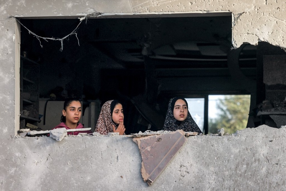 Girls peer through the hole left by a destroyed window from a building in Rafah in the southern Gaza Strip following Israeli air strikes overnight.