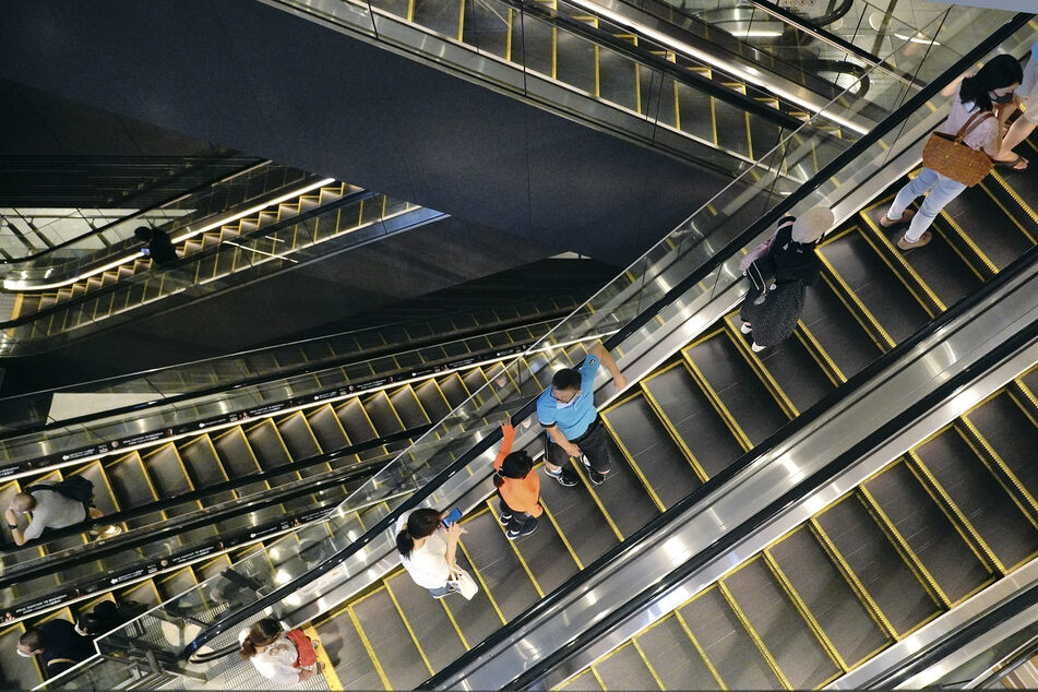 Menschen fahren in einem Einkaufsgebäude mit einer Rolltreppe.