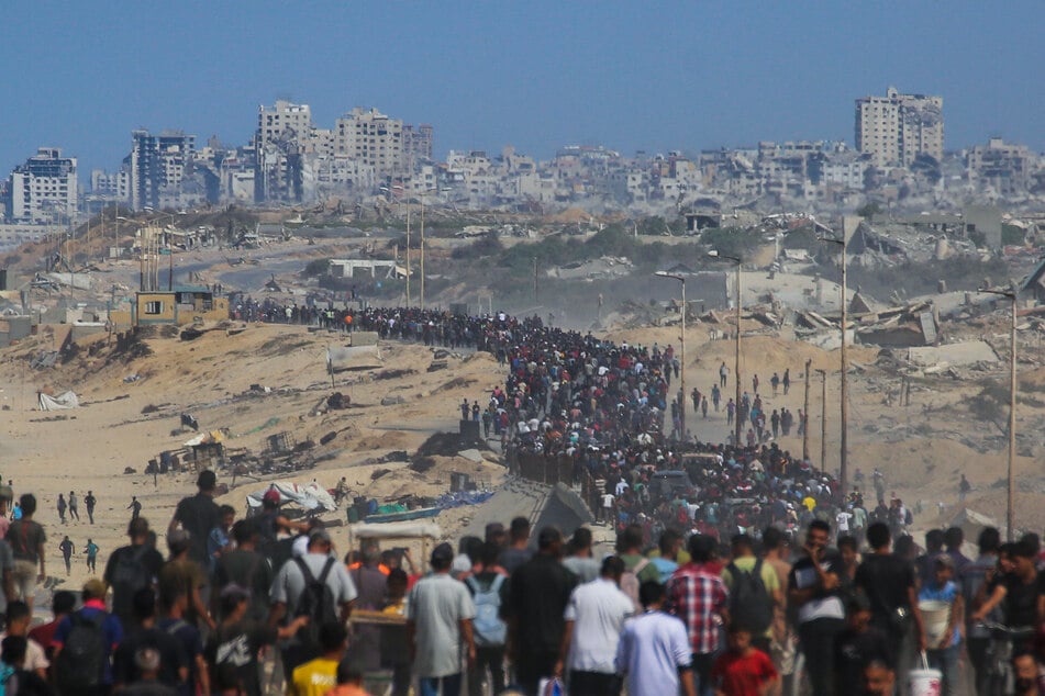 Palestinians walk along Al-Rashid road toward Gaza City from Nuseirat in the central Gaza Strip on October 10, 2025.
