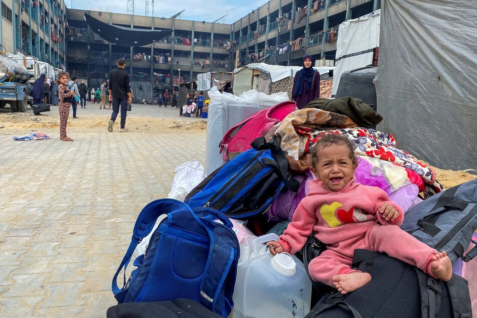 A child in Jabalia sitting atop belongings cries as displaced Palestinians flee areas in the northern Gaza Strip following an Israeli evacuation order.