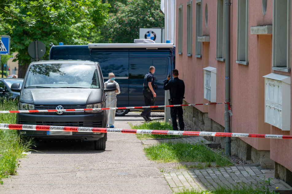Einsatzkräfte stehen vor dem abgesperrten Mehrfamilienhaus. In einer Wohnung wurde am Dienstag eine tote Person gefunden.
