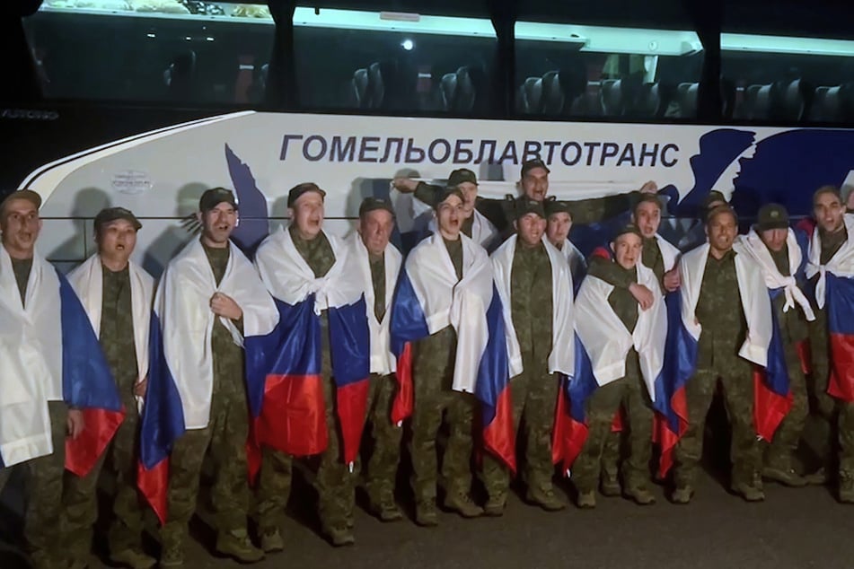 Auf diesem Foto posieren russische Soldaten mit Nationalflaggen in einem Gebiet in Belarus, nachdem sie im Rahmen eines Kriegsgefangenenaustauschs zwischen Russland und der Ukraine aus der Gefangenschaft zurückgekehrt sind.