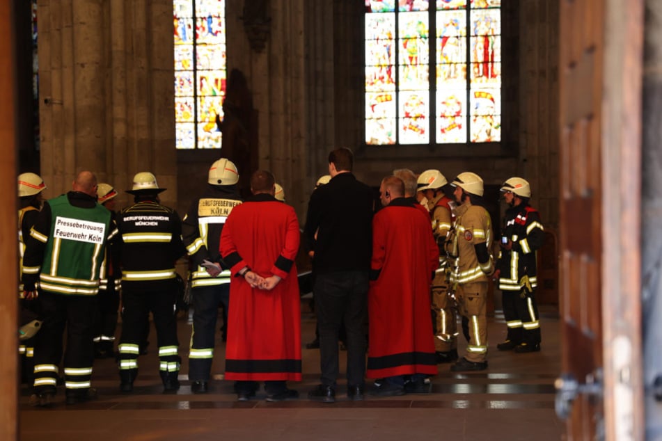 Feuerwehrkräfte und Domschweizer haben im Inneren des Kölner Doms die Lage und das Vorgehen besprochen.