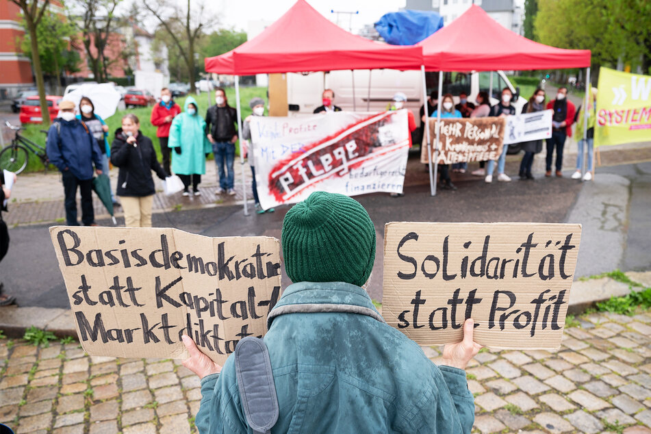Teilnehmer einer Kundgebung des Deutschen Gewerkschaftsbundes (DGB) stehen anlässlich des Internationalen Tags der Pflege mit Transparenten auf der Blasewitzer Straße.