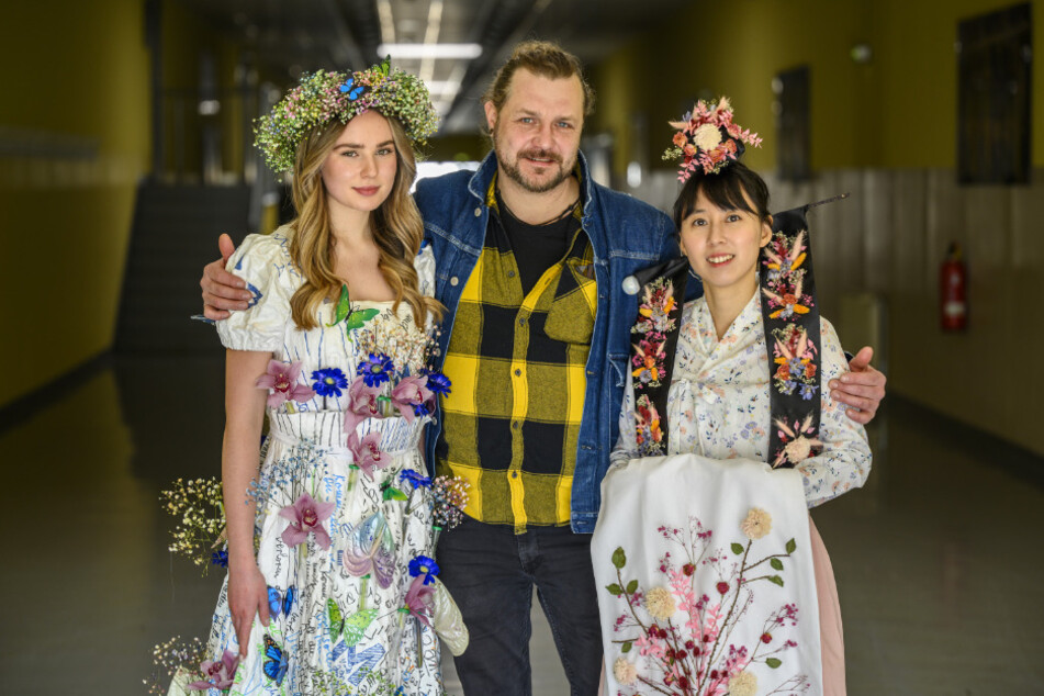 Floristmeister David Gehrisch zeigt die Kleider an Messemitarbeiterin Tabea Pohle (19, l.) und Floristin Gaeun Sager (34).