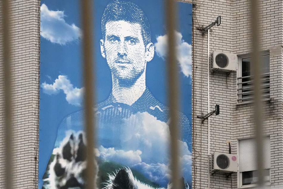 Ein Wandplakat, das den serbischen Tennisspieler Novak Djokovic (34) zeigt, hängt an einen Gebäude.