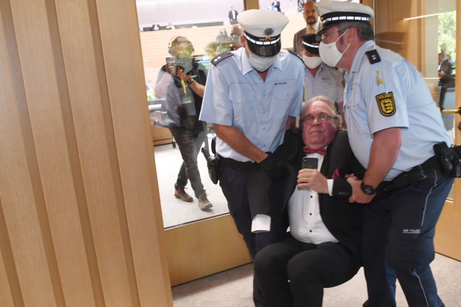 Heinrich Fiechtner (parteilos, M) wird von Polizeibeamten aus dem Landtag von Baden-Württemberg getragen.