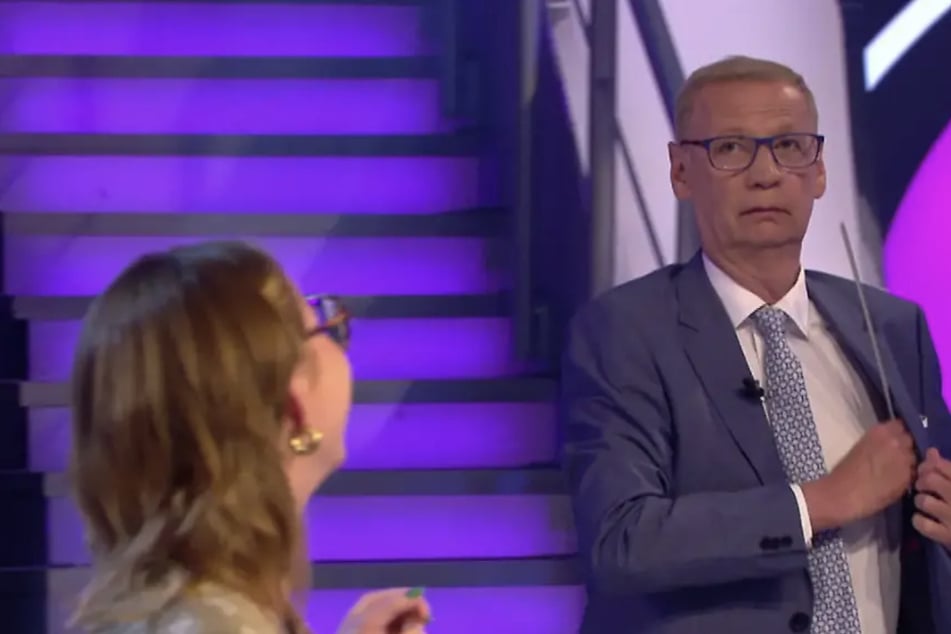 Der 70-jährige Moderator lässt die abgebrochene Leiste kurzerhand in seinem Sakko verschwinden.