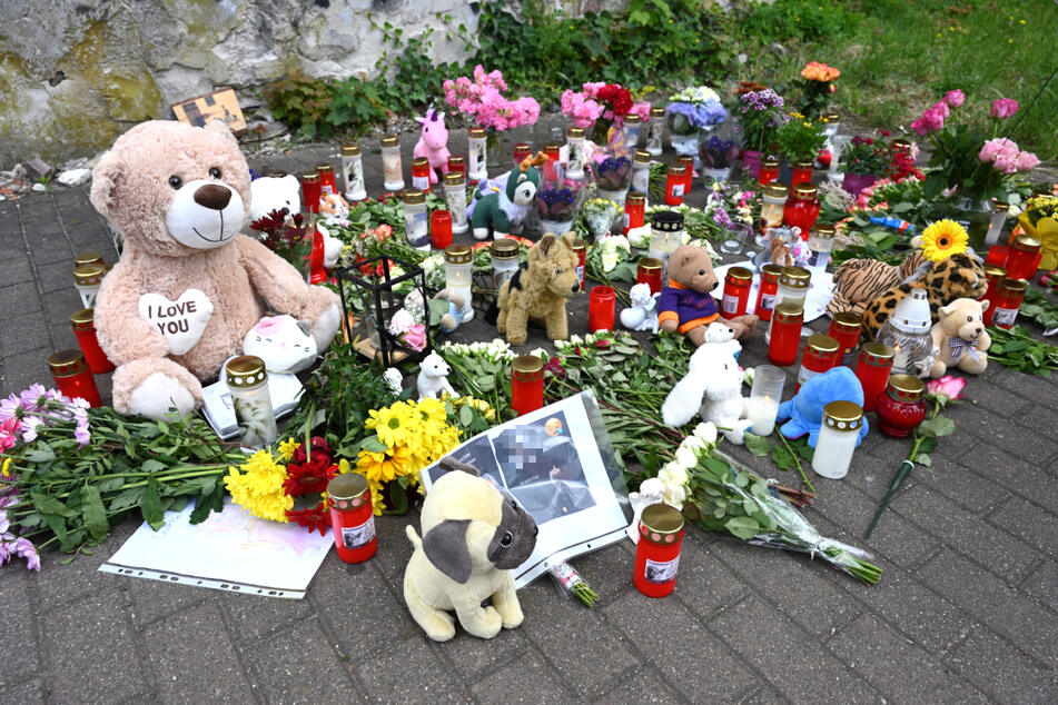 Menschen legen Blumen, Kerzen und Kuscheltiere ab und gedenken der Schülerin.