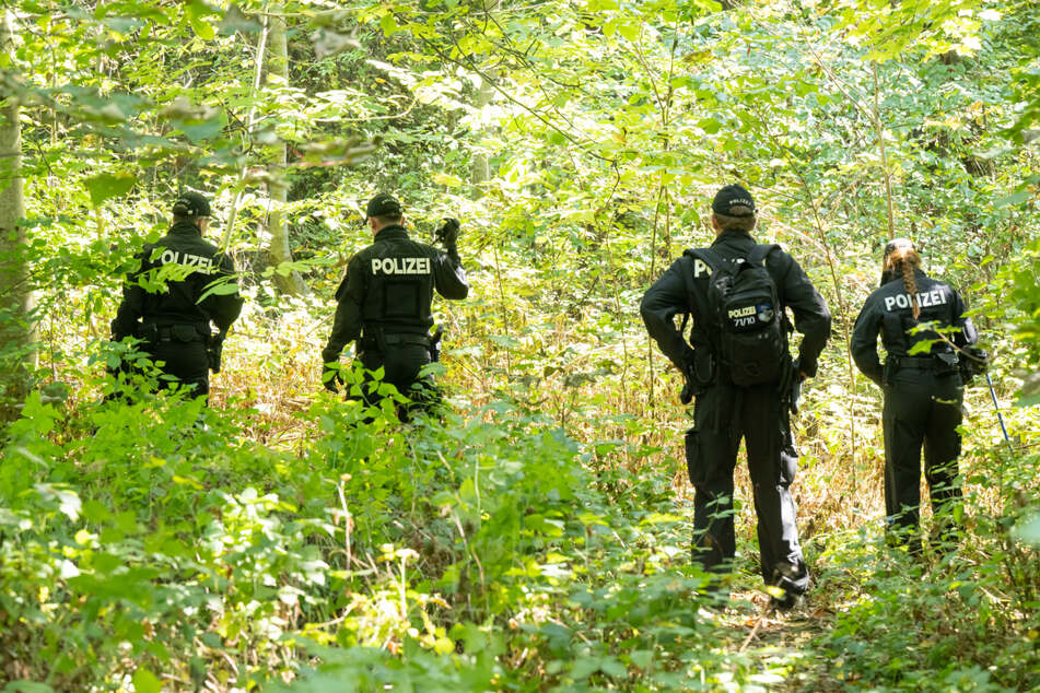 Polizisten durchsuchen das Waldstück, in dessen Nähe die Leiche in einem Auto entdeckt wurde. (Archiv)