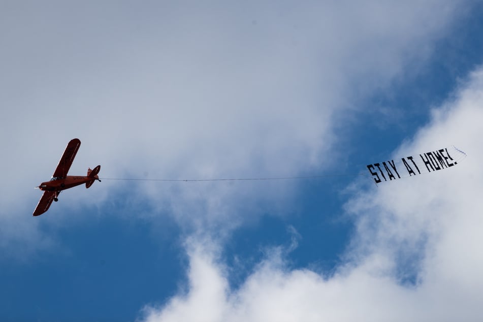 Ein kleines Flugzeug fliegt mit einem Banner mit der Aufschrift "Stay at Home!" (Bleibt zu Hause!) über Hamburg. 