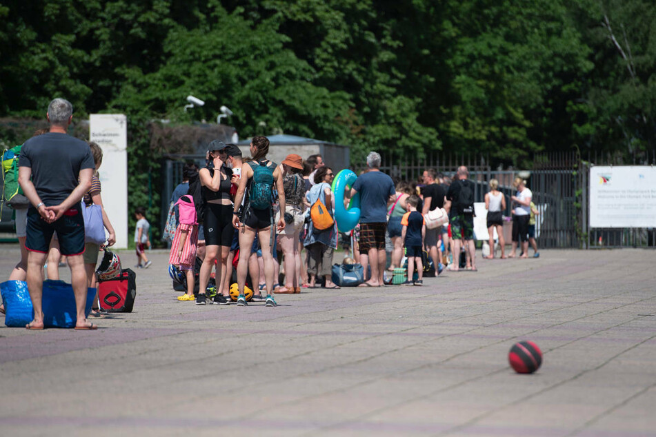 Menschen stehen bei warmem Wetter in einer Schlange vor dem Eingang zum Olympiabad in Niederfinow. Im Zuge der Corona-Lockerungen haben die Freibäder in Brandenburg bei warmem Sommerwetter einen guten Zulauf verzeichnet.