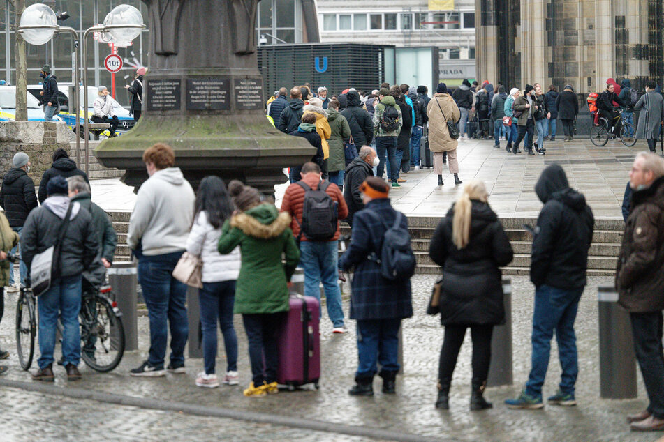Menschen stehen in einer langen Schlange für ihre Impfung im Kölner Dom an.