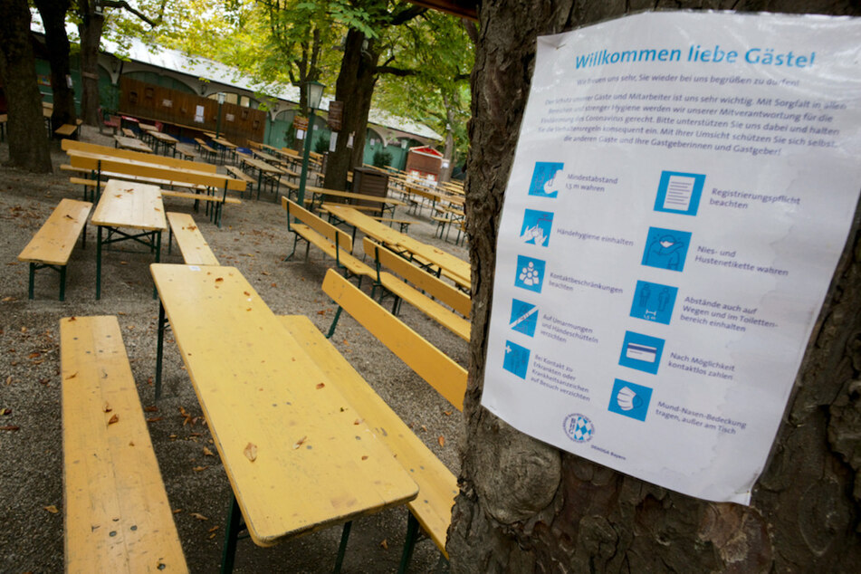 Ein Hinweisschild mit den Corona-Verhaltensregeln hängt am Baum eines leeren Biergartens in München.