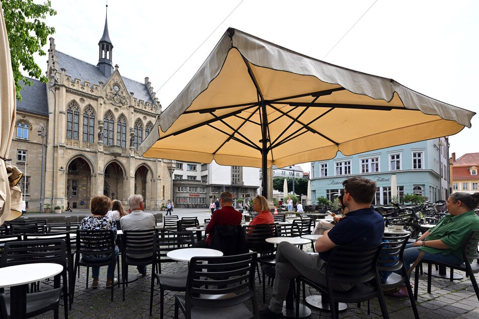 Tische, Stühle und Sonnenschirme stehen vor den Restaurants am Fischmarkt in der Erfurter Altstadt. (Archivbild)