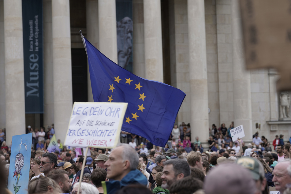 Teilnehmer einer Demonstration gegen Rechtsextremismus zur Europawahl stehen mit einer Europaflagge vor der Glyptothek auf dem Königsplatz.