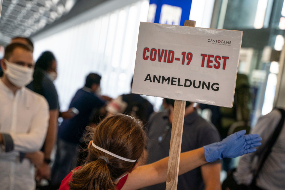 Eine Bedienstete weist in einem Terminal des Frankfurter Flughafens den Weg zur Anmeldung für einen Corona-Test.