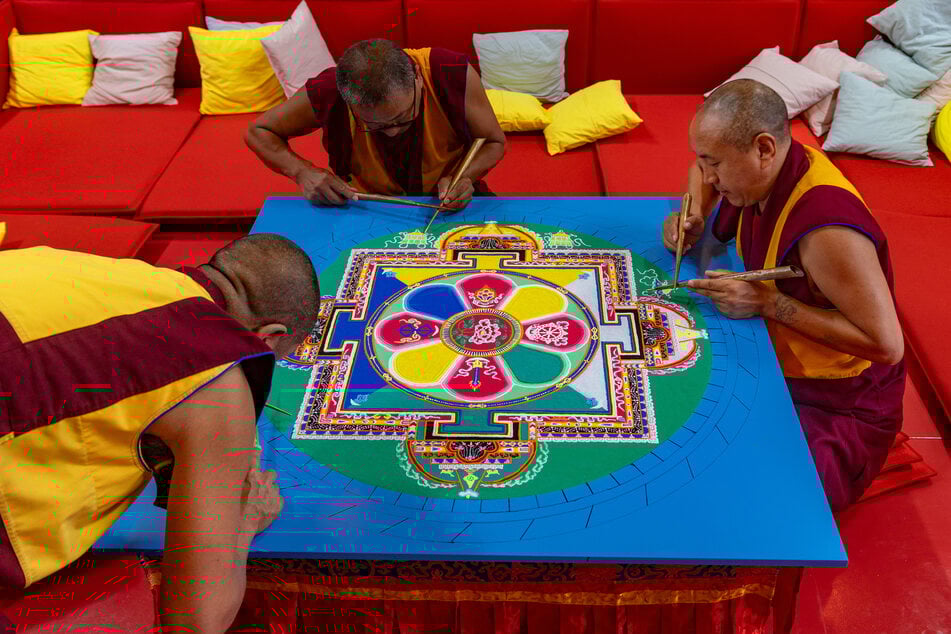 Die Mönche fertigen das Sand-Mandala nach einer Vorlage.