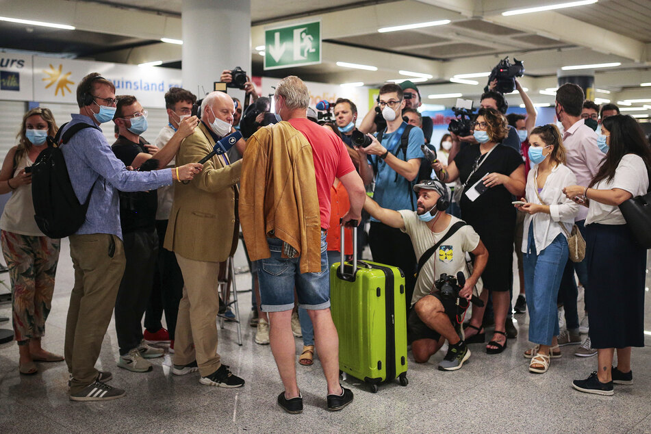 Ein Fluggast (M) vom morgendlichen TUI-Flug Düsseldorf-Mallorca wird am Flughafen Son Sant Joan von Journalisten interviewt.