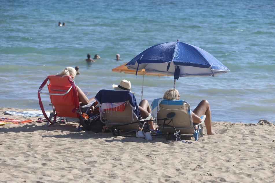 Menschen genießen die Sonne am Strand von El Arenal in Palma de Mallorca. Deutschlands zweitgrößter Reisekonzern DER Touristik hofft auf ein starkes zweites Halbjahr 2021.