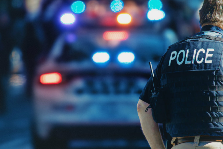 Ein amerikanischer Polizist mit Waffengurt steht hinter seinem Auto. (Symbolbild)